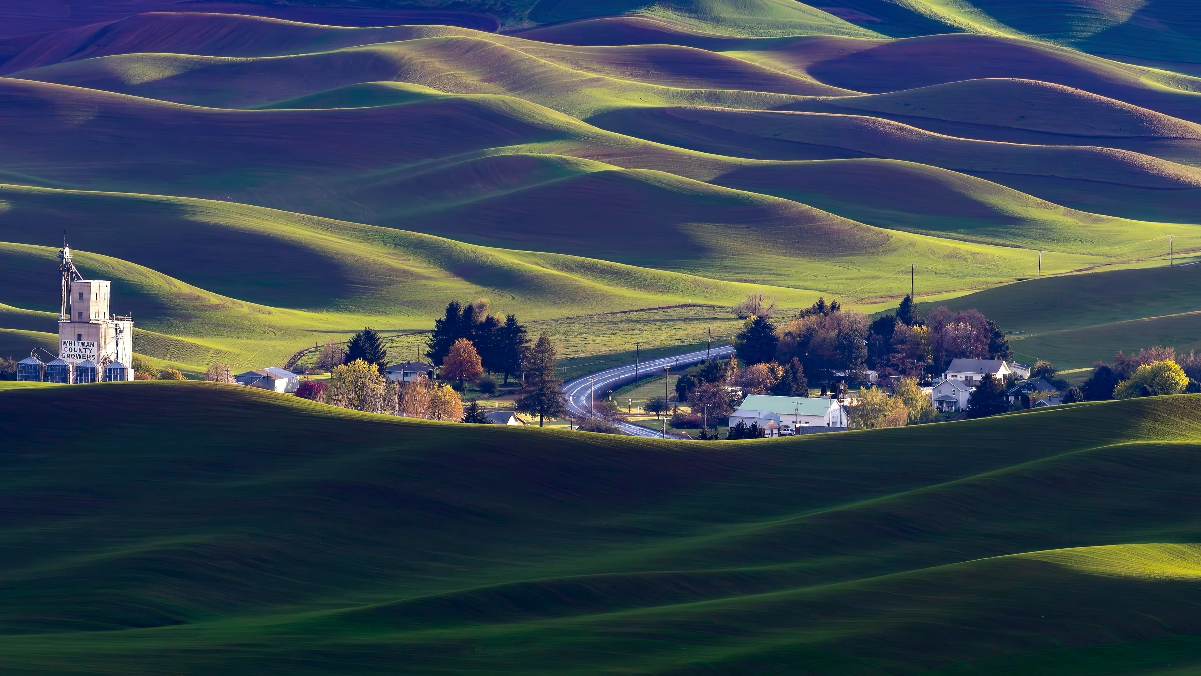 Small farming community nestled in a valley surrounded by rolling Palouse hills in golden afternoon light